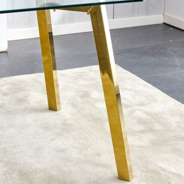 4e29af79a14e4b9a9a65e545f7877ee0_9b798907538e807848b6b38b0194c3d0 71 * 35.4 inch rectangular dining table. The transparent tempered glass tabletop is paired with golden 7-shaped metal table legs, showcasing a minimalist texture. Suitable for various places.