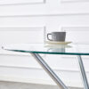 Round clear glass dining table with a unique shape for 4-6 people, with ring-shaped gathered silver metal legs, suitable for desks, kitchens, terraces, dining rooms.